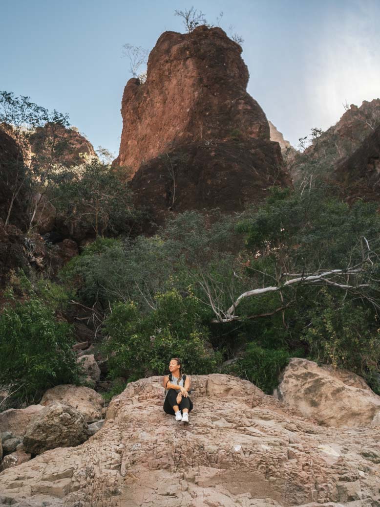 Une fille assise sur un rocher dans un canyon - Nomade Amoureux